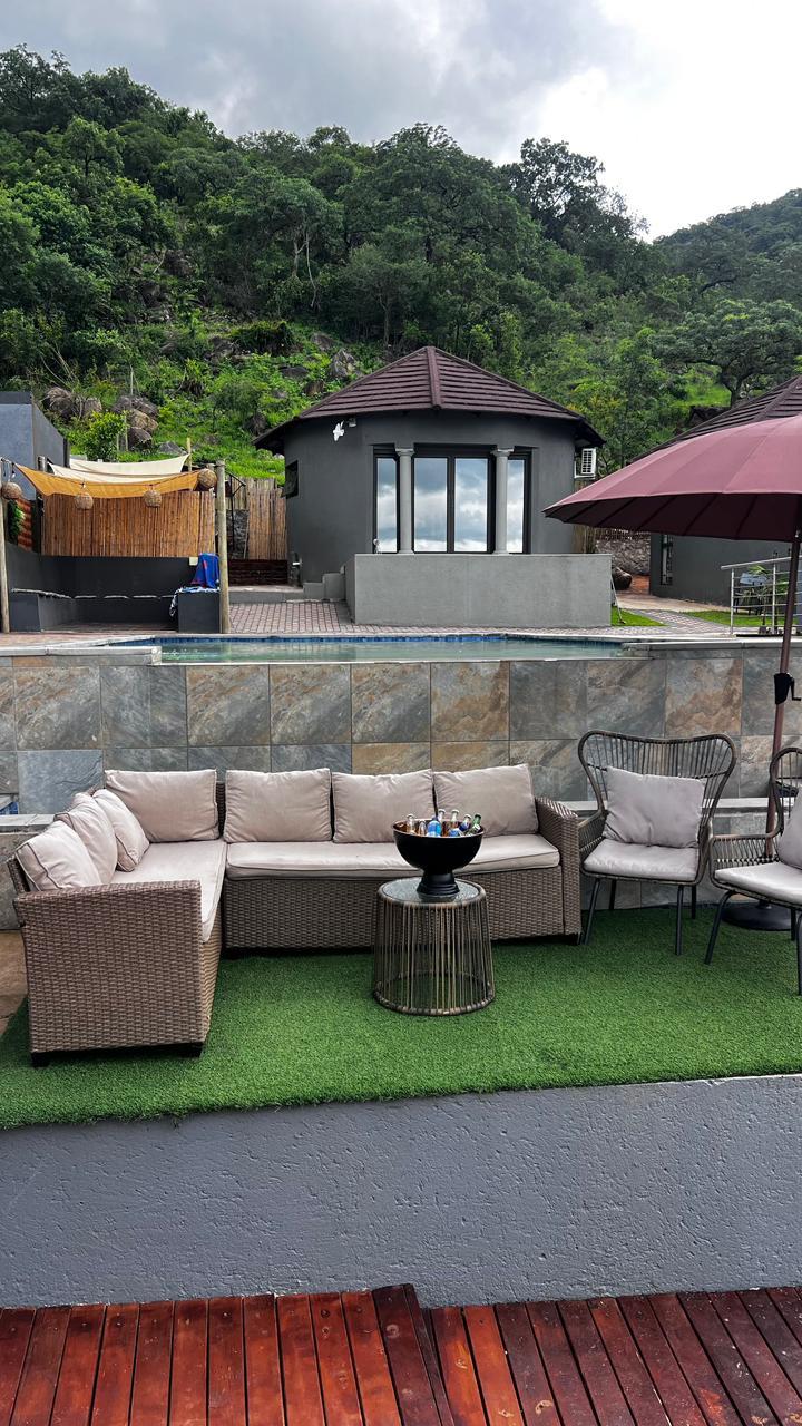 Outdoor lounge seating beside the pool with the bush hillside above the lodge