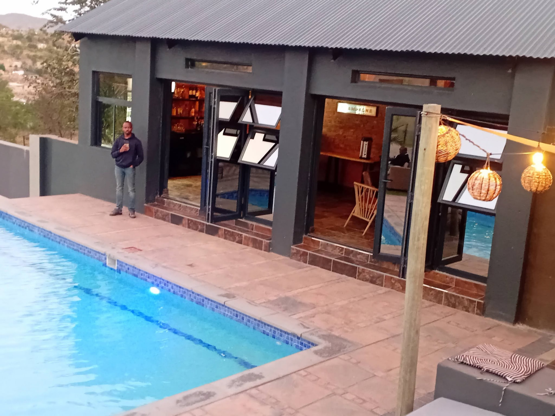 Lodge bar opening onto the poolside deck at dusk with lantern lighting